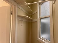 Closet with built-in shelves and a frosted window, offering natural light and practical storage space.