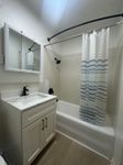 Bright modern bathroom featuring a sleek vanity, polished faucet, and a stylish shower area with a striped curtain.