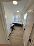 Bright and cozy bedroom featuring a stylish desk, comfortable chair, and large windows for natural light.