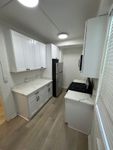 Modern kitchen with sleek white cabinetry, marble countertops, and stainless steel appliances, offering a bright and inviting space.