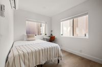 Bright and inviting bedroom with large windows and a stylish workspace.
