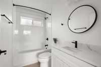Modern bathroom with sleek white fixtures, round mirror, and elegant marble countertop.