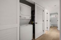 Convenient in-unit laundry area with a modern stackable washer and dryer next to a bathroom entrance.