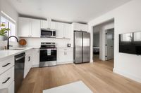 Contemporary kitchen with sleek white cabinetry, modern appliances, and hardwood floors.