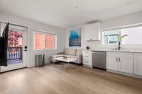 Apartment with a spacious kitchen, cozy living area, and sleek hardwood floors. Abundant natural light from large windows creates an inviting atmosphere.