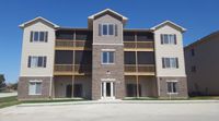 Modern three-story apartment building with stylish brick facade, inviting balconies, and ample window views on a sunny day.