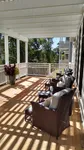 Charming sunlit community porch with cozy wicker chairs and vibrant potted plants, offering a serene outdoor space.