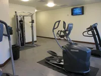 Modern apartment gym featuring state-of-the-art elliptical, treadmill, and multi-functional weight machine in a well-lit space.
