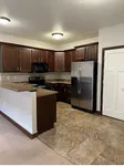 Modern kitchen with elegant dark wood cabinetry, sleek stainless steel appliances, and stylish tile flooring.