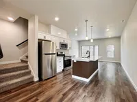 Modern open-concept kitchen in a bright apartment featuring stainless steel appliances, elegant countertops, and chic pendant lighting with stunning wood flooring.