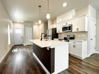 Modern kitchen with sleek white cabinetry, stainless steel appliances, and elegant island under stylish pendant lighting.