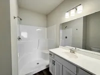 Elegant bathroom featuring a modern shower, sleek white vanity, and bright lighting for a refreshing ambiance.