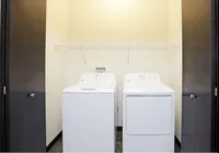 Modern laundry room featuring new washer and dryer, with ample shelving for added convenience.