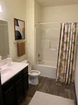 Modern bathroom with elegant dark wood cabinets, stylish abstract art, and patterned shower curtain for a contemporary touch.