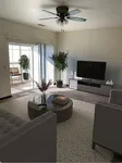 Contemporary living room with sleek furniture, large TV, and natural light from glass doors leading to a charming balcony with plants.