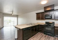 Inviting open floor plan with modern kitchen featuring dark cabinetry, sleek appliances, and large patio doors for natural light.
