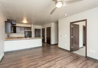 Modern open-plan living area featuring elegant hardwood floors, a sleek kitchen with dark cabinetry, and ample natural light.