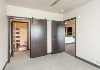 Inviting room with contemporary barn doors leading to a modern bathroom and kitchen, showcasing sleek interior design.