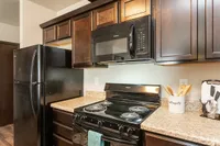 Modern kitchen with sleek black appliances, rich wooden cabinets, and elegant granite countertops creating a sophisticated atmosphere.