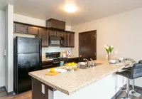 Modern kitchen with sleek dark wood cabinets, a spacious granite island, and contemporary bar stools, ideal for entertaining.