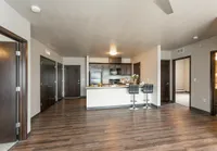Contemporary open-concept apartment with sleek kitchen, modern cabinetry, inviting breakfast bar, and elegant wood flooring.