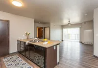 Modern open-concept apartment kitchen and living area with sleek countertops, stylish lighting, and expansive floor-to-ceiling windows.
