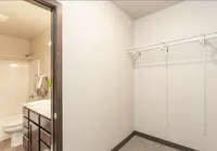 Bright and modern apartment closet with open shelving and an adjacent luxurious bathroom featuring sleek cabinetry.