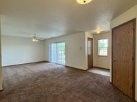 Spacious living area with plush carpeting, natural light through large sliding doors, and cozy ambiance.