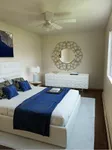 Elegant bedroom with a plush white bed, chic decor, and modern dresser, featuring a stylish mirror and warm natural lighting.