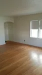 Bright and inviting empty room with beautiful hardwood flooring and large windows ensuring ample natural light.