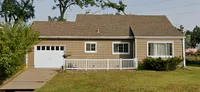 Charming single-story home with a welcoming front porch, spacious driveway, and lush green lawn.