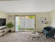 Bright and inviting living room with modern decor, featuring a plush blue sofa, elegant artwork, and large sliding glass doors leading to a serene outdoor view.