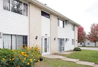 Charming apartment complex exterior with vibrant flower garden and autumn foliage, inviting entrance for a welcoming ambiance.