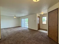 Spacious living area with elegant carpeting, large windows for natural light, and convenient sliding doors leading to a patio.