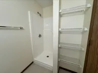Modern bathroom with a sleek shower and spacious wire shelving, offering convenient storage and a minimalist design.