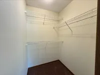 Spacious walk-in closet with sleek white wire shelving, offering ample storage space in a modern apartment.
