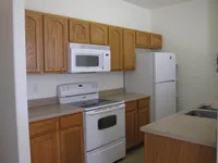 Charming kitchen with modern white appliances, sleek countertops, and warm wooden cabinetry, perfect for culinary enthusiasts.