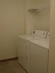 Spacious laundry room featuring a modern washer and dryer set with convenient shelving for storage.