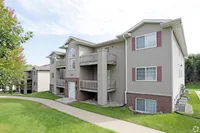 Charming apartment building with spacious balconies, nestled among lush greenery and a peaceful pathway.
