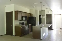 Modern kitchen with sleek dark wood cabinets, contemporary appliances, and elegant pendant lighting over the island, perfect for culinary enthusiasts.