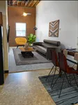 Chic apartment interior with modern decor, featuring a cozy living area with a stylish sofa and vibrant yellow chair, complemented by elegant dining space and artistic accents.