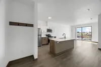 Modern open-plan kitchen and living area with sleek appliances and a bright, spacious feel. Large windows offer ample natural light and a view of the outdoor landscape.