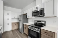Modern kitchen with sleek stainless steel appliances, stylish white cabinetry, and elegant wood flooring.