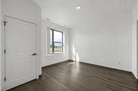 Bright and modern room with natural light streaming through a large window, featuring sleek hardwood floors and crisp white walls.