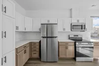 Modern kitchen with sleek stainless steel appliances, elegant white cabinetry, and a spacious countertop offering a bright and welcoming atmosphere.