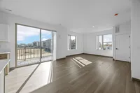 Bright and spacious living area with large windows, wooden flooring, and an inviting balcony view, perfect for modern living.