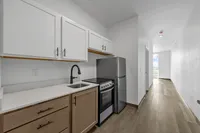Sleek modern kitchen with elegant cabinetry, stainless steel appliances, and inviting natural light down a spacious hallway.