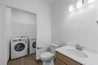 Chic bathroom with in-unit laundry, featuring modern washer and dryer, sleek vanity, and bright lighting.