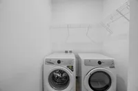 Modern laundry room with sleek washer and dryer, bright white walls, and efficient wire shelving.