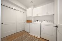 Modern in-unit laundry room with sleek white cabinetry, efficient full-sized washer and dryer, and elegant sliding doors.